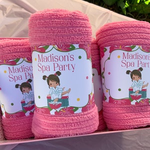 K&ouml;nnte beinhalten: Drei rosa Handt&uuml;cher mit einem Blumendesign und dem Text "Madison's Spa Party" auf jedem. Die Handt&uuml;cher befinden sich in einer rosa Geschenkbox mit wei&szlig;en Punkten.