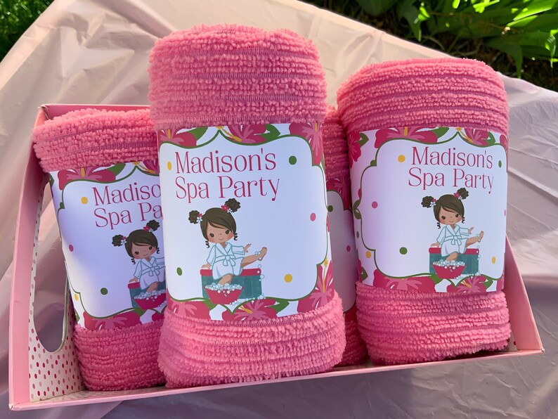 K&ouml;nnte beinhalten: Drei rosa Handt&uuml;cher mit einem Blumendesign und dem Text "Madison's Spa Party" auf jedem. Die Handt&uuml;cher befinden sich in einer rosa Geschenkbox mit wei&szlig;en Punkten.
