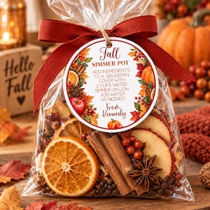 May include: A clear plastic bag filled with dried orange slices, cinnamon sticks, star anise, and red berries, tied with a dark red ribbon. A round tag features the text Fall Simmer Pot, instructions to add 2 cups water, and From Kennedy.