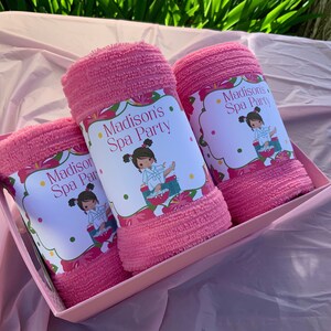 K&ouml;nnte beinhalten: Drei rosa Handt&uuml;cher in einer rosa Box mit einem Blumendesign und dem Text "Madison's Spa Party" auf jedem Handtuch.