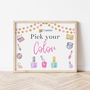 May include: A printable sign with the text "Pick your Color" in pink and black lettering. The sign is decorated with a gold and pink garland, makeup brushes, lipstick, eyeshadow palettes, and nail polish bottles.