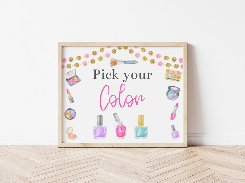 May include: A printable sign with the text "Pick your Color" in pink and black lettering. The sign is decorated with a gold and pink garland, makeup brushes, lipstick, eyeshadow palettes, and nail polish bottles.