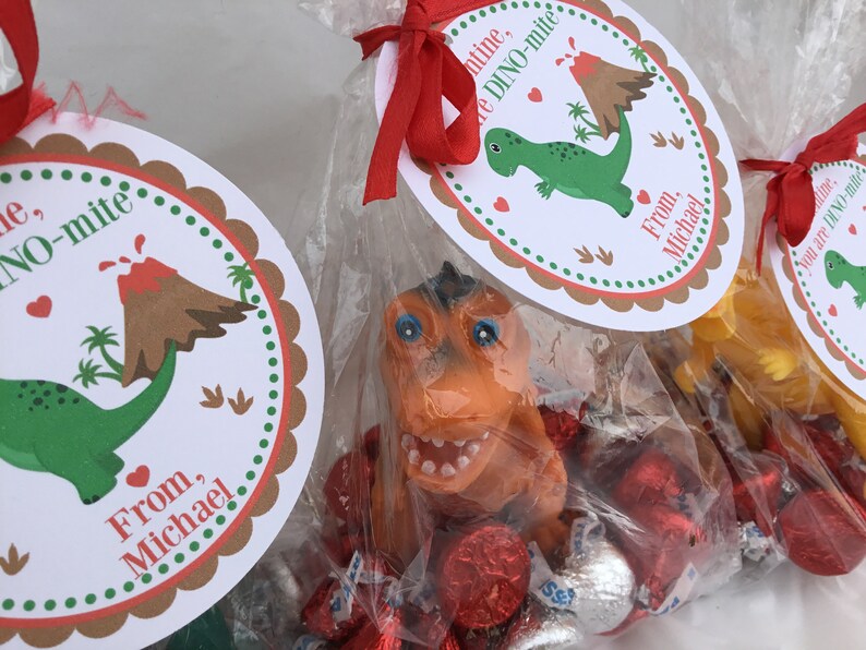 Puede incluir: Un conjunto de tres bolsas de golosinas para el D&iacute;a de San Valent&iacute;n con etiquetas de tem&aacute;tica de dinosaurios. Cada bolsa contiene caramelos de chocolate rojos y plateados y un peque&ntilde;o juguete de dinosaurio. Las etiquetas dicen "You are DINO-mite" y "From, Michael".