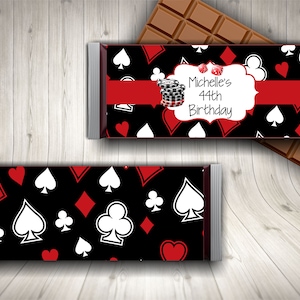 Puede incluir: Un envoltorio de chocolate negro y rojo con un patr&oacute;n de naipes blancos. El envoltorio tiene un &oacute;valo blanco con el texto "Michelle's 44th Birthday" y una cinta roja.