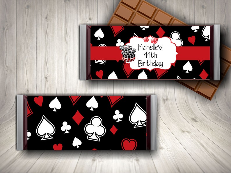 Puede incluir: Un envoltorio de chocolate negro y rojo con un patr&oacute;n de naipes blancos. El envoltorio tiene un &oacute;valo blanco con el texto "Michelle's 44th Birthday" y una cinta roja.
