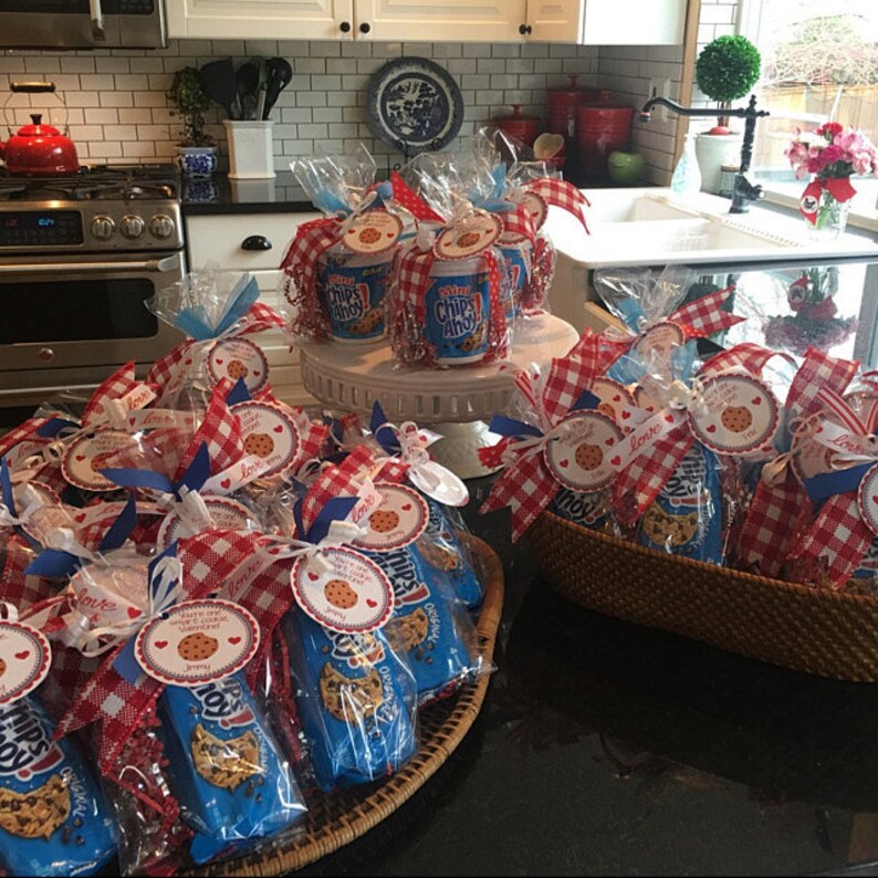 May include: A table with multiple bags of Chips Ahoy cookies wrapped in red and white gingham fabric and blue ribbon. Each bag has a tag with a heart and the text "You are one smart cookie!"