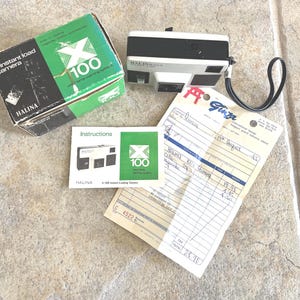 May include: A vintage Halina X100 instant load camera with its original box and instruction manual. The box is green and black with the text "X instant load camera". A receipt from "Ginza" is also present.