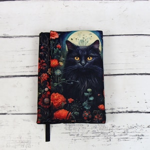 Könnte beinhalten: Schwarze Katze mit gelben Augen in einem Feld mit roten Blumen unter einem Vollmond. Das Bild ist auf einem schwarzen Stoffbuchcover gedruckt.
