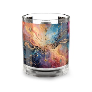 May include: A clear glass tumbler with a colorful, abstract design. The artwork features swirling patterns in shades of blue, orange, gold, and purple. The design has a celestial or cosmic theme, with star-like accents.