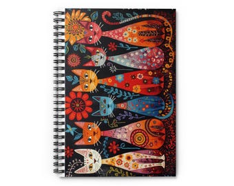 Op de afbeelding: Spiraalgebonden notitieboek met een kleurrijke illustratie van zes gestileerde katten. Elke kat heeft een andere kleur en is versierd met bloemmotieven. De achtergrond is zwart met extra bloemaccenten. Het ontwerp van het notitieboek is grillig en artistiek.