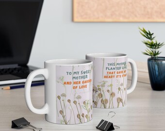 Może przedstawiać: Dwa białe ceramiczne kubki z kwiatowymi wzorami i inspirującym tekstem. Kubek po lewej stronie ma napis "To my sweet mother and her garden of love". Kubek po prawej stronie ma napis "This mother planted love that gave my heart it's start".