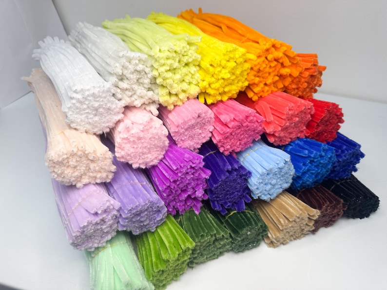 May include: A collection of colorful pipe cleaners in various shades, including white, pink, purple, green, blue, yellow, orange, red, and brown. These craft supplies are bundled together, showcasing their soft, fuzzy texture.