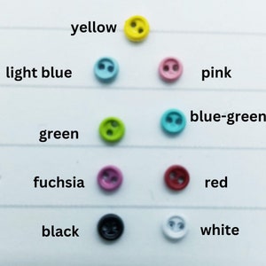 May include: Assortment of 10 two-hole buttons in various colours, including yellow, light blue, pink, blue-green, green, fuchsia, red, black, and white.