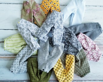 May include: A collection of 10 pairs of trousers in various colours and patterns, including floral, polka dot, plaid, and striped. The trousers are made from different fabrics, such as cotton and linen.