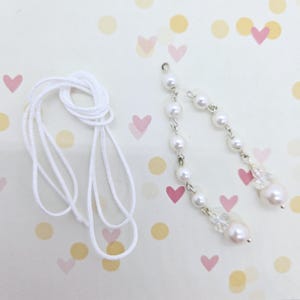 May include: Two white pearl strands with crystal accents and a white cord for making jewellery.