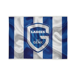 Op de afbeelding: Een wit-blauwe gestreepte vlag met een blauw schild in het midden. Het schild heeft een witte letter "G" met de woorden "LADIES" en "KRC GENK" in witte tekst.