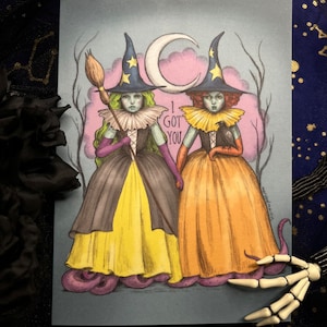 May include: Two witches with purple and yellow dresses and pointed hats stand on purple octopus tentacles. The text "I got you" is written in the background.