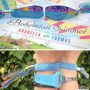 May include: Two colorful wristbands with the text "Bohemian Summer" printed on them. The wristbands are tied together with a yellow ribbon. The wristbands are on a person's wrist.