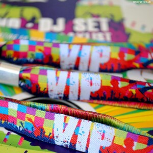 May include: Colorful wristbands with the word "VIP" printed in white. The wristbands have a checkered pattern and feature a crowd of people in the background.