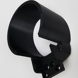 Op de afbeelding: Een zwart, 3D-geprint object met een gebogen, cilindrische vorm en een rechthoekige basis. De basis heeft verschillende ronde gaten. Het object lijkt gemaakt te zijn van een solide, matzwart materiaal.