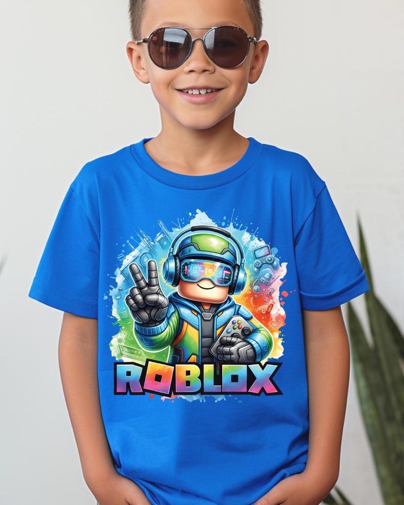 A smiling boy wearing a vibrant blue t-shirt with a colorful Roblox character wearing headphones and sunglasses with a large Roblox logo.