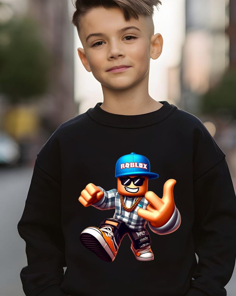 以下が含まれることがあります： 黒いスウェットシャツ。青い Roblox ロゴ入りのキャップ、サングラス、金のチェーンを身に着けた、カラフルな Roblox キャラクターが描かれています。キャラクターは手のジェスチャーをしています。スウェットシャツは若い人が着ています。