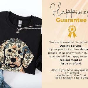 May include: Black sweatshirt featuring a floral dog design in beige, blue, and peach tones. A silver necklace with a small pendant is visible. The image also includes text that reads "Happiness Guarantee."