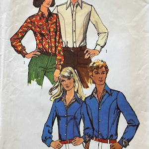 Puede incluir: Una taza de cerámica blanca con asa negra y el texto "But First, Coffee" en negrita negra. La taza se encuentra sobre un fondo borroso, sugiriendo un ambiente acogedor.