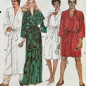 May include: A Very Easy Very Vogue sewing pattern envelope 8155 in size medium. The illustration shows four robe variations: a long white robe, a long green robe with a black leaf print, a short white robe, and a short red robe, all with tie belts.