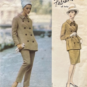 May include: Vintage Vogue Couturier Design sewing pattern. The pattern features two illustrations of women's outfits. One woman is wearing a tan double-breasted coat and matching pants. The other is wearing a tan double-breasted jacket and skirt.