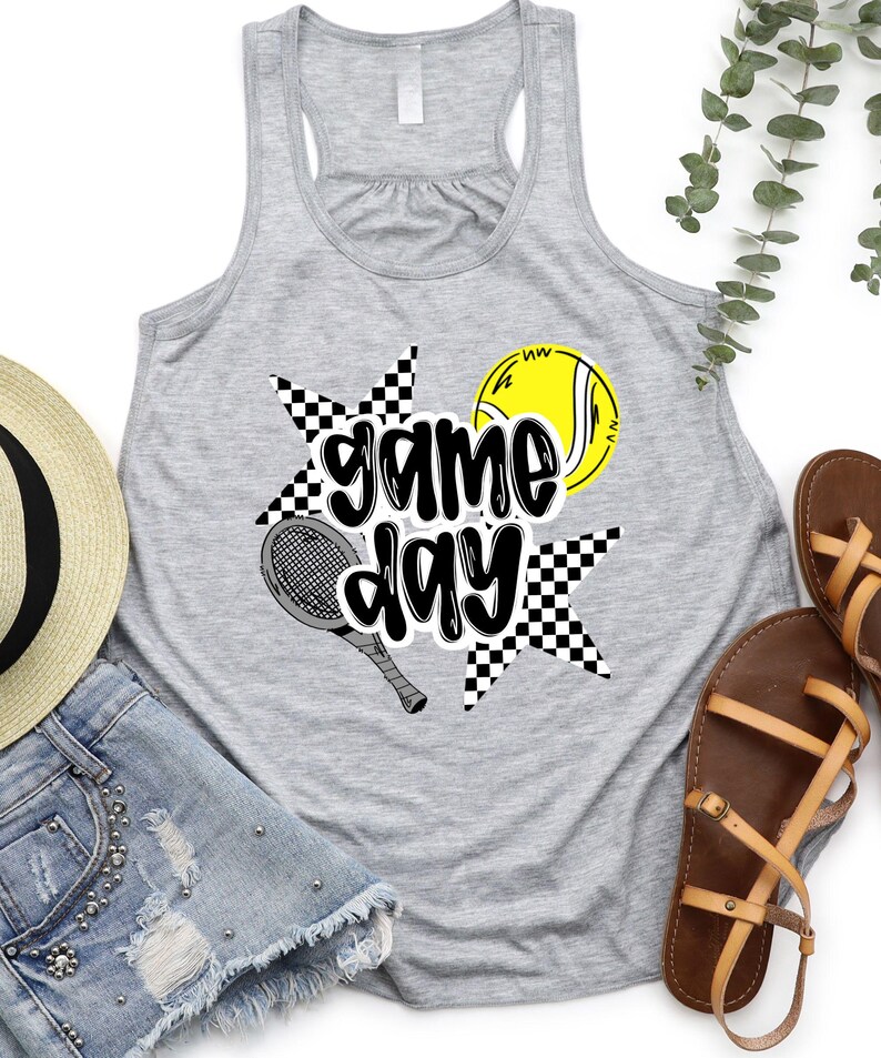 a gray tank top with a graphic design, a pair of denim shorts, a straw hat, and a pair of sandals, all laid out on a white background.