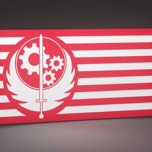 May include: A rectangular red and white flag featuring a white emblem. The emblem includes a gear, two smaller gears, a sword, and wings. The flag has red and white horizontal stripes.