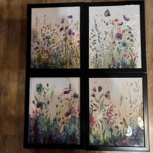 Peut inclure: Quatre œuvres d'art florales encadrées. Chacune présente une représentation détaillée et colorée de fleurs sauvages et de verdure. L'œuvre est placée sur un fond clair, avec un cadre noir. Le thème général est la nature et la botanique.