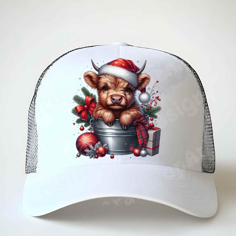 May include: White trucker hat with a black mesh back. The front features a festive illustration of a brown Highland cow wearing a Santa hat, nestled in a metal bucket with Christmas decorations, including a red bow and ornaments.