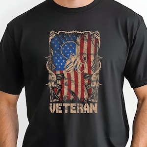 May include: Black t-shirt with a distressed American flag design, two crossed rifles, dog tags, and the word "VETERAN" printed in white.