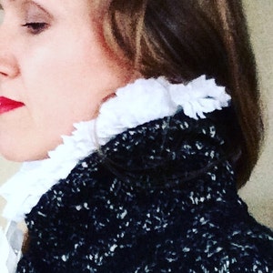 May include: A black and white speckled jacket with a white frilled collar. The jacket is worn by a person with brown hair and red lipstick.