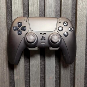 Könnte beinhalten: Ein matt-schwarzer PlayStation 5 DualSense Wireless-Controller. Der Controller verfügt über ein Steuerkreuz, Aktionstasten und Analogsticks. Das PlayStation-Logo befindet sich unter dem Touchpad. Der Controller ist für Spiele konzipiert.