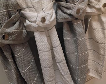 May include: A set of four hanging kitchen towels featuring a textured waffle weave pattern in alternating shades of white and gray. Each towel is secured with a silver-toned metal snap button, creating a folded loop design for easy hanging.