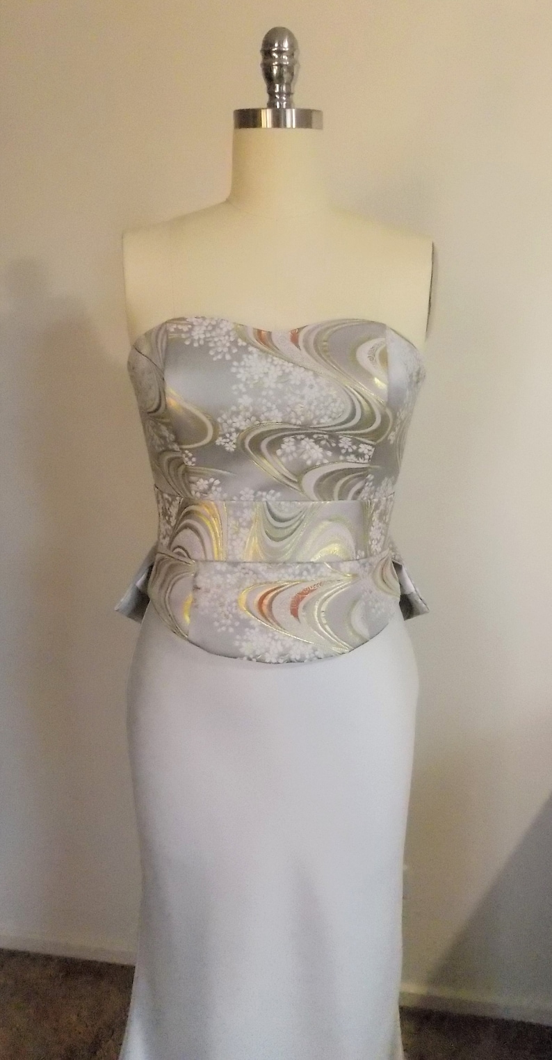 Puede incluir: Un vestido de novia sin tirantes con un corpi&ntilde;o estampado en plata y blanco y una falda fluida.