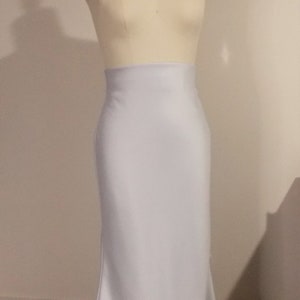 Puede incluir: Una falda blanca ajustada con silueta de sirena. La falda est&aacute; hecha de una tela suave y sedosa y tiene una cintura alta.