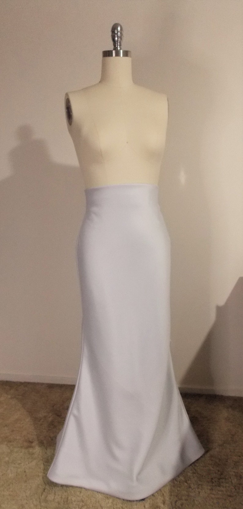 Puede incluir: Una falda blanca ajustada con silueta de sirena. La falda est&aacute; hecha de una tela suave y sedosa y tiene una cintura alta.