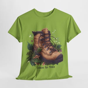 Op de afbeelding: Groen T-shirt met een illustratie van een bruine wandelschoen en de tekst "Leave No Trace" gedrukt op de voorkant.