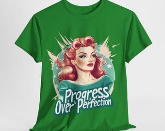 May include: Green t-shirt with a retro illustration of a woman with red hair and the text "Progress Over Perfection." The design features a teal and white colour scheme with star accents, creating a vintage aesthetic.