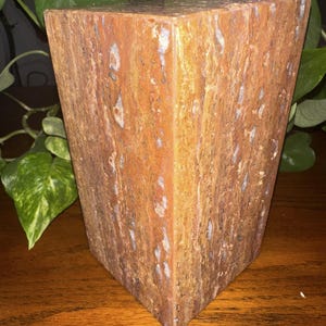 May include: A rectangular block of brown, orange, and white marble with a textured surface.
