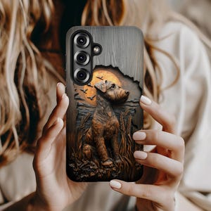 May include: A phone case featuring a detailed illustration of a dog in a field with a sunset and birds. The case has a wood-grain texture and a cutout for the phone's camera.