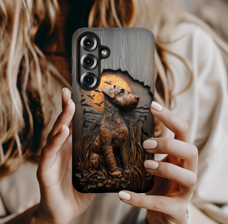 May include: A phone case featuring a detailed illustration of a dog in a field with a sunset and birds. The case has a wood-grain texture and a cutout for the phone's camera.