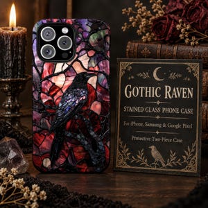 May include: A phone case featuring a black raven perched on a branch against a stained glass background of red, purple, and black hues. Next to it is a black card with the text GOTHIC RAVEN STAINED GLASS PHONE CASE For iPhone, Samsung & Google Pixel.