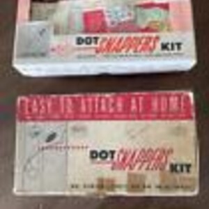 May include: Two boxes of a "Dot Snappy" kit. The top box is white with red lettering and a red and white design. The bottom box is red with white lettering and a white and red design. Both boxes have a picture of a white dog with a red nose.