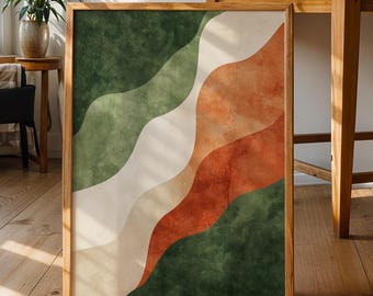May include: A framed abstract art print featuring a design of layered, wavy shapes in shades of green, white, and orange. The artwork is displayed on a wooden floor, leaning against a wall, with natural light illuminating the room.
