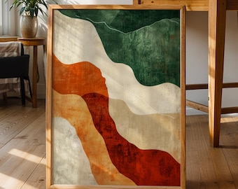 May include: A framed abstract art print featuring a landscape design with layered shapes in shades of green, orange, and red. The artwork is displayed on a wooden floor, with natural light illuminating the room. The frame is made of light-colored wood.